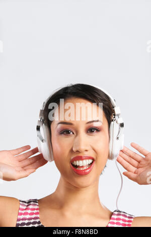 Studio shot di donna ascoltando la musica attraverso le cuffie Foto Stock
