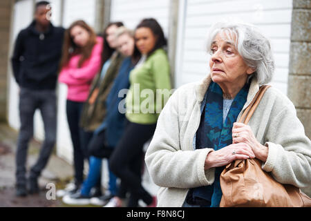 Senior sentimento donna intimidire da un gruppo di giovani Foto Stock