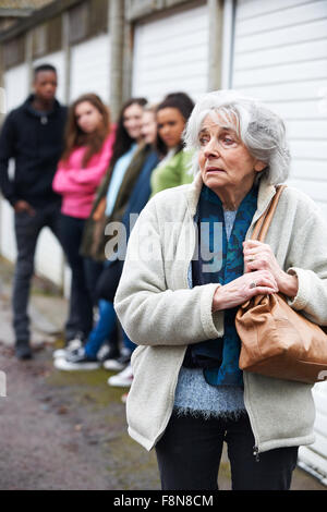 Senior sentimento donna intimidire da un gruppo di giovani Foto Stock