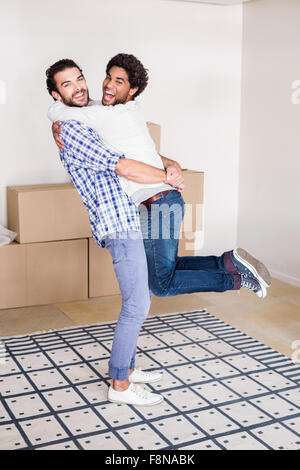 Felice coppia gay abbracciando nella nuova casa Foto Stock