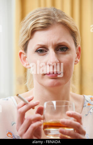 Donna che mantiene un bicchiere di whisky e sigaretta Foto Stock