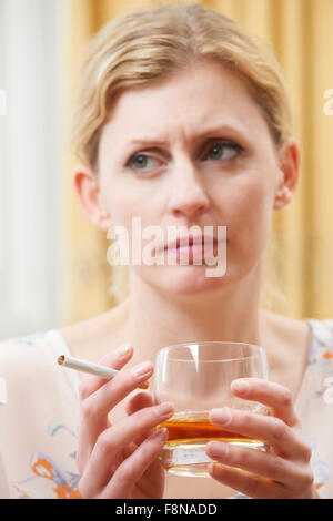 Donna che mantiene un bicchiere di whisky e sigaretta Foto Stock