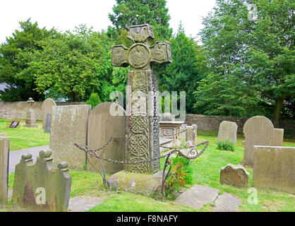 Croce celtica nel sagrato della chiesa di San Lorenzo, chiesa nel villaggio di Eyam, Peak National Park, Derbyshire, in Inghilterra, Regno Unito Foto Stock