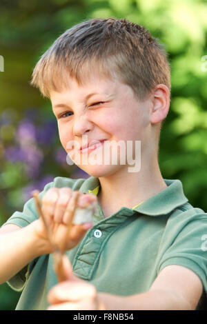 Ragazzo puntando Slingshot in giardino Foto Stock