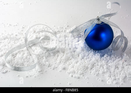 Decorazione per albero di Natale deep blue ball con arco di argento nella neve su sfondo bianco Foto Stock