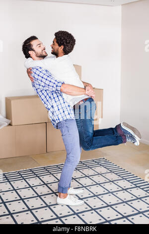 Felice coppia gay abbracciando nella nuova casa Foto Stock