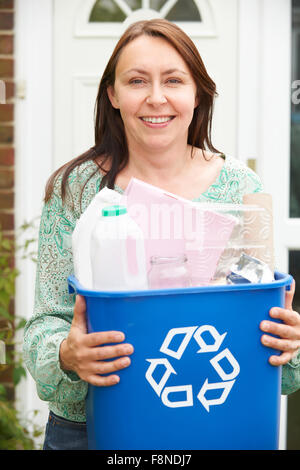 Donna di mezza età che porta il contenitore di riciclaggio Foto Stock