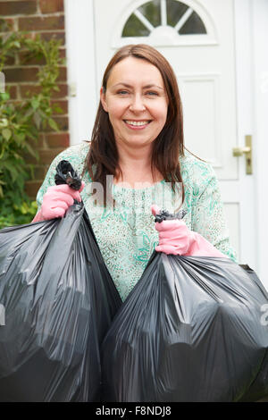 Donna tenendo fuori Garbage in sacchi Foto Stock