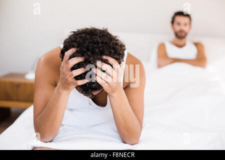 Turbato uomo seduto sul letto in primo piano Foto Stock