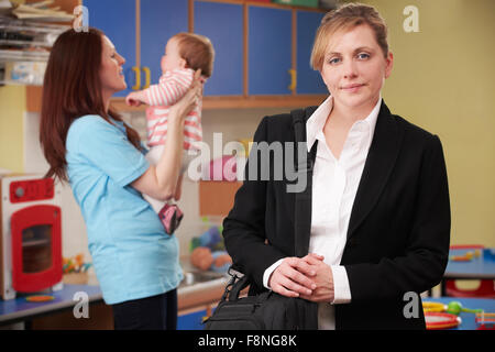 Madre di lavoro facendo cadere il bambino al vivaio Foto Stock