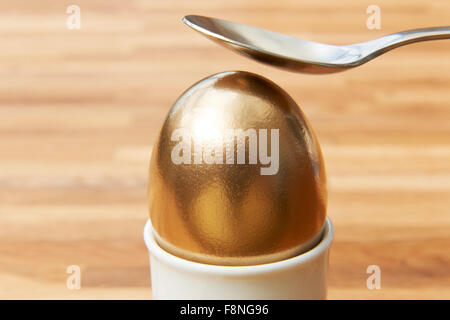 Cracking cucchiaio Golden Egg Foto Stock