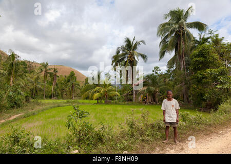 Un agricoltore in piedi dal suo le risaie e la sua casa Foto Stock