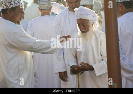 Tre uomini chat della vivace giovedì mercato del bestiame in Nizwa, Oman Foto Stock