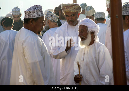 Tre uomini chat della vivace giovedì mercato del bestiame in Nizwa, Oman Foto Stock