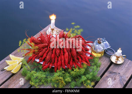 Ciotola di gamberi di fiume sul molo sul lago con candele e aquavit in Svezia Foto Stock