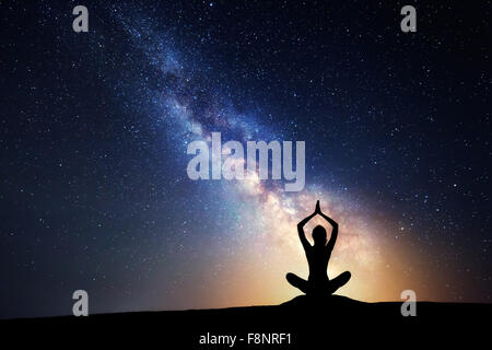 Via Lattea. Cielo notturno con stelle e silhouette di donna pratica dello yoga. Foto Stock
