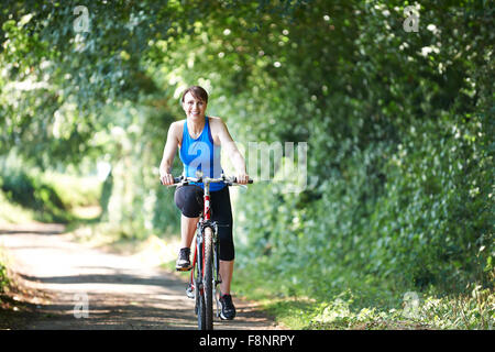 Donna di mezza età ciclismo su strada di campagna Foto Stock