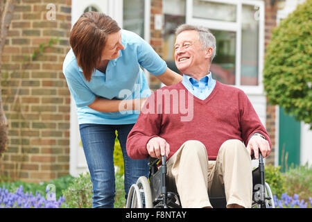 Accompagnatore con Senior uomo in sedia a rotelle Foto Stock