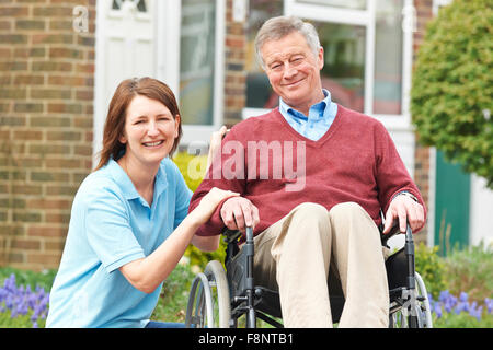 Accompagnatore con Senior uomo in sedia a rotelle Foto Stock