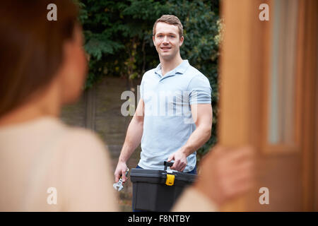 Donna apertura porta a Repairman Foto Stock