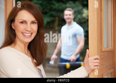 Donna apertura porta a Repairman Foto Stock