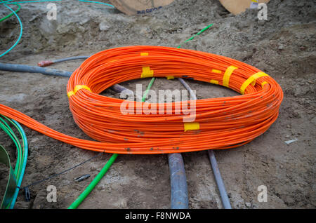Orange fascio di cavi in fibra ottica su un sito in costruzione Foto Stock