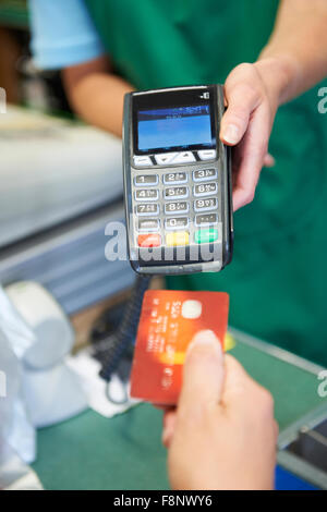 Il cliente utilizzando la macchina per le carte di credito per pagare in un supermercato Foto Stock