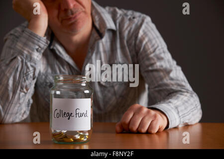 Premuto Un uomo guarda il vaso vuoto etichettati College Fund Foto Stock