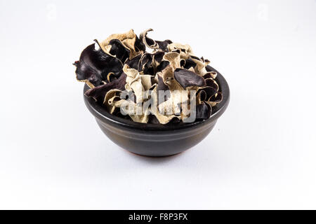 Nero vaso in ceramica con funghi secchi impilati in, Auricularia polytricha, Cloud orecchio o fungo cinese fungo nero. Close up Foto Stock