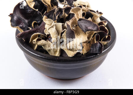 Nero vaso in ceramica con funghi secchi impilati in, Auricularia polytricha, Cloud orecchio o fungo cinese fungo nero. Close up Foto Stock