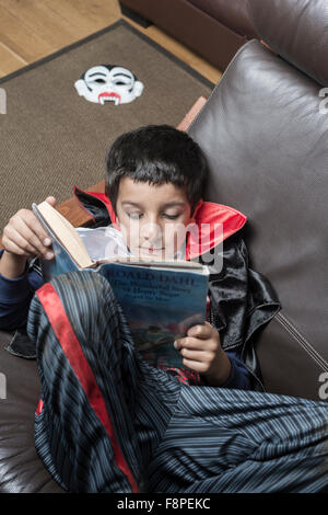 Ragazzo,8,in abito di Halloween la lettura di un libro Foto Stock