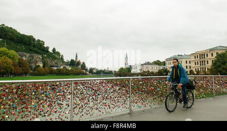 Uomo in bicicletta nell'amore blocca i lucchetti sul ponte Makartsteg oltre il Fiume Salzach Salisburgo in Austria Foto Stock