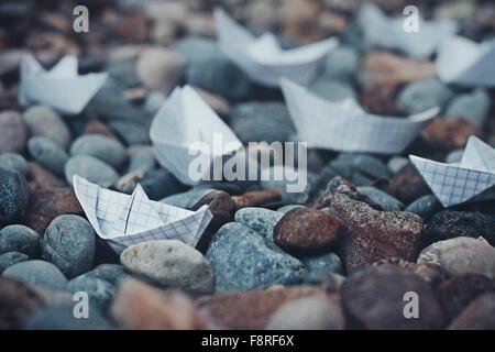 Barche di origami e ciottoli sulla spiaggia Foto Stock