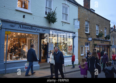 Persone, comprese le famiglie con bambini, il late night Shopping di Natale in strada a buon mercato, Sherborne, Inghilterra. Foto Stock