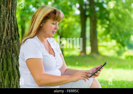 50 anno vecchia donna con un tablet in estate park Foto Stock
