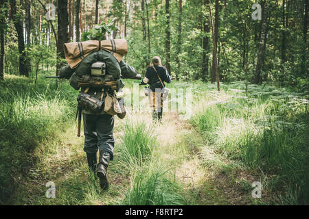 Unidentified re-enactors vestiti come i soldati tedeschi in esecuzione attraverso la foresta di estate Foto Stock