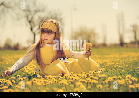 Bambina godendo la soleggiata giornata di primavera nei campi di fiori. vintage-look Foto Stock