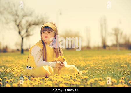 Bambina godendo la soleggiata giornata di primavera nei campi di fiori. vintage-look Foto Stock