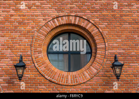 Splendidamente rinnovato e parete di una vecchia fabbrica tessile con finestra rotonda e due lanterne Foto Stock