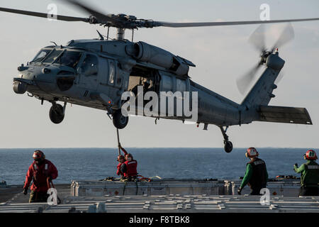 I marinai collegare un carico pendente su un MH-60S Seahawk, Sikorsky SH-60/MH-60 Seahawk, dal "Isola Cavalieri" di elicottero di mare squadrone di combattimento (HSC) 25 sul ponte di volo dell'U.S. La marina è solo distribuita portaerei USS Ronald Reagan. Foto Stock