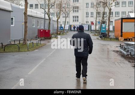 Dresden, Germania. Undicesimo Dec, 2015. Un membro dello staff della compagnia di sicurezza passeggiate attraverso un ricovero di emergenza per i rifugiati per motivi di l'aeroporto di Dresda, Germania, 11 dicembre 2015. La casa provvisoria che si trova su un parcheggio offre rifugio per un massimo di 600 rifugiati. Foto: Sebastian Kahnert/dpa/Alamy Live News Foto Stock