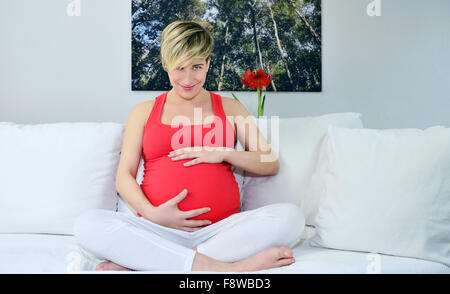 Donna incinta con twin bambinos, mani in ascolto dello stomaco Foto Stock