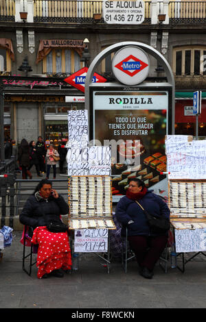 Madrid, Spagna 11 dicembre 2015: Donne che vendono biglietti per la lotteria di Natale accanto all'ingresso della stazione della metropolitana Sol in Plaza Puerta del Sol nel centro di Madrid. La lotteria di Natale spagnola è una delle più antiche al mondo e la più grande al mondo in termini di pagamento totale. Il biglietto vincente è noto come "El Gordo" ("il grande" o "il grasso"). Crediti: James Brunker / Alamy Live News Foto Stock