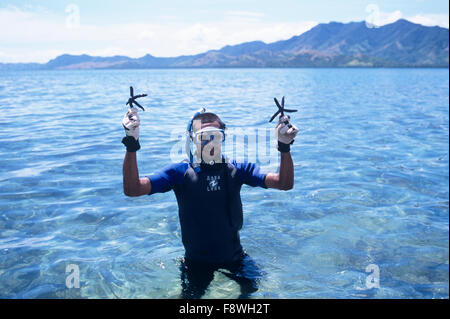 Isole Fiji, Nukubati Island Resort, personale subacqueo con Blue Sea Star stella di mare, Linckia laevigata Foto Stock