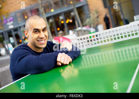 Giovane uomo in posa tenendo una tabella racchetta da tennis Foto Stock