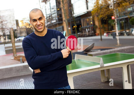 Giovane uomo in posa tenendo una tabella racchetta da tennis Foto Stock