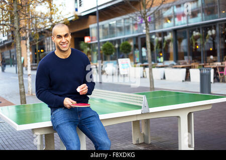 Giovane uomo in posa tenendo un ping pong racket e sfera Foto Stock