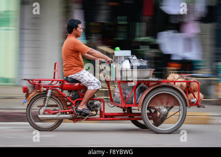 Il panning fotografia immagine di un uomo tailandese accelerando lungo una strada di città Foto Stock