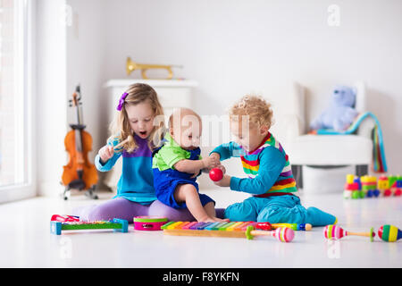 I bambini con strumenti musicali. Educazione musicale per i bambini. In legno colorato giocattoli d'arte. Bambina e ragazzo riprodurre musica. Foto Stock