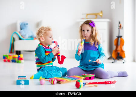 I bambini con strumenti musicali. Educazione musicale per i bambini. In legno colorato giocattoli d'arte. Bambina e ragazzo riprodurre musica. Foto Stock